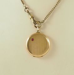 A delightful antique Edwardian period gold filled circular locket in rose gold tone. The front with a brushed finish with a single ruby, 3mm in diameter, the ground imitating bamboo(?). The reverse with the bamboo pattern. Opening directly at  the bail. With space for two photographs with both frames and plastic coverings. The chain is for display only. Germany 1900-1910. 7.6g The space for photographs 2.5cm in diameter. In inches 1". The locket 3.1cm in diameter.   In inches 1 1/4". With bail 4 Historical Gold Jewelry For Weddings, Formal Rose Gold Jewelry With Vintage Charm, Historical Medallion Jewelry For Gift, Antique Locket Necklace With Vintage Charm For Formal Occasions, Formal Vintage Charm Locket Necklace, Collectible Round Heirloom Locket Necklace, Historical Yellow Gold Jewelry For Wedding, Formal Antique Finish Round Pendant Jewelry, Antique Round Jewelry For Vintage Collection