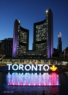 there is a sign that says toronto in front of the water fountain with lights on it