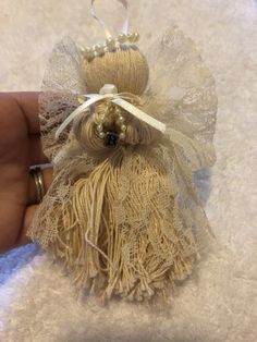 a hand is holding a small ornament made out of twine and burlap