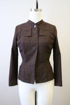 "Description: 1940s brown wool jacket, with an amazing geometric appliqued design. Button front with long sleeves. It has a hook and eye closure at the top button. Shaped, nipped waist with padded shoulders. Fully lined. Condition: In fair condition, with no stains. It has scattered moth holes over the body, sleeves, and cuffs (see the photos). It is missing two front buttons, although the buttons are very simple and would be fairly easy to replace. Designer: Adrian Stated Size: n/a Measurements Brown Stand Collar Blazer With Button Closure, Brown Blazer With Button Closure And Stand Collar, Brown Stand Collar Blazer With Buttons, Brown Single Breasted Blazer With Stand Collar, Brown Blazer With Stand Collar And Buttons, Vintage Stand Collar Blazer For Work, Vintage Blazer With Stand Collar For Work, Fitted Brown Blazer With Hidden Button Closure, Fitted Brown Outerwear With Hidden Button Closure