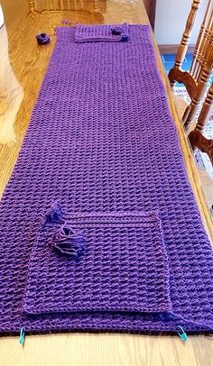 a purple crocheted table runner sitting on top of a wooden dining room table