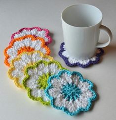 four crocheted coasters are next to a coffee cup