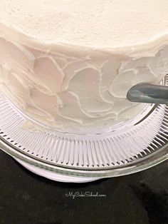 a close up of a cake with frosting on a glass plate near a knife