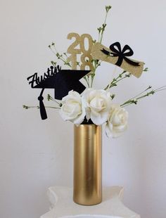 a gold vase filled with white flowers on top of a table