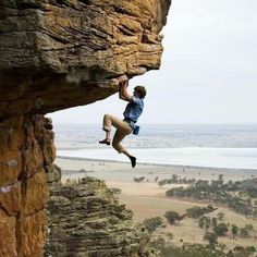 a man climbing up the side of a cliff with his feet in the air while holding onto a rope