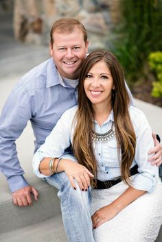 a man and woman are sitting on the steps smiling at the camera while posing for a photo