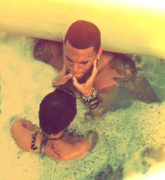 two people sitting in a bathtub talking on their cell phones while one person holds his hand up to his ear