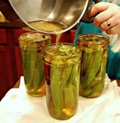 a person pouring pickles into jars on a table