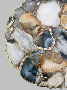 an abstract piece of art made out of agate and gold leafy material with black, white, gray and blue colors