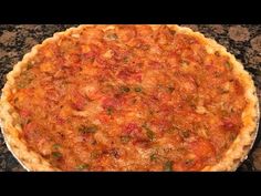 a pizza sitting on top of a metal pan covered in cheese and toppings next to a black granite counter