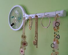 there are many necklaces hanging on the wall next to a rack with earring hooks