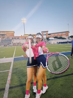 two female tennis players hugging each other with rackets in their hands on the court