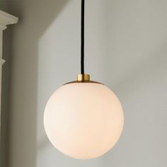 a white light hanging from a ceiling fixture in a room with gray walls and windows