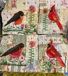 two red birds sitting on top of quilts