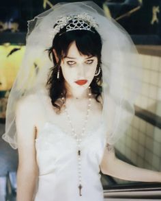 a woman in a wedding dress with a veil over her head and red lipstick on her lips