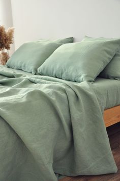 a bed with green sheets and pillows on it