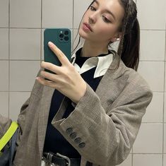 a woman taking a selfie with her cell phone in front of her face and wearing a blazer