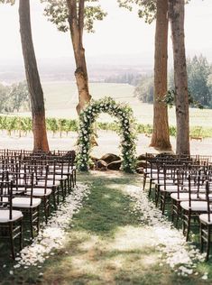 an outdoor ceremony setup with white flowers and greenery on the aisle, surrounded by trees