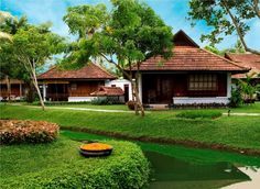 the house is surrounded by lush green grass and trees, along with a small pond