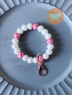 a pink and white bracelet with a gold clasp on a blue plate that says fresh'n boos