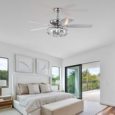 a bedroom with a bed, ceiling fan and two windows that look out onto the outdoors