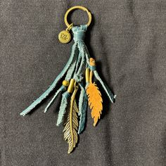 a keychain with feathers hanging from it's side on a gray cloth