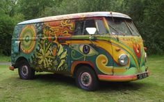 an old vw bus painted with flowers and leaves is parked in a grassy area