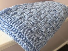 a blue crocheted blanket sitting on top of a window sill next to a wall