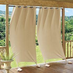 two white curtains hanging from a wooden porch