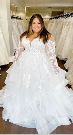 a woman standing in front of wedding dresses