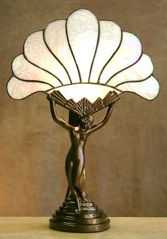 a table lamp with a woman holding a fan on it's head and arms