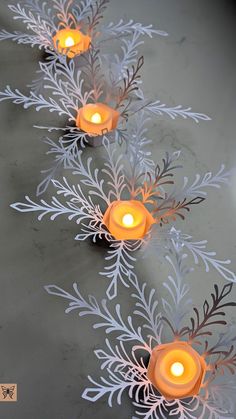 candles are lined up in the shape of snowflakes with leaves and branches on them