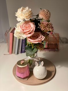 a vase filled with flowers sitting on top of a table next to a book shelf