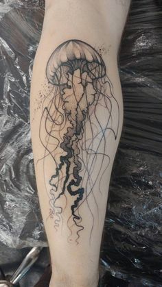 a man's leg with a tattoo of a jellyfish in black ink on it