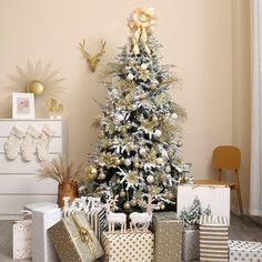 a christmas tree with presents under it in front of a white and gold decorated wall