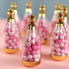 pink and white candies in glass bottles with gold caps on a pink tablecloth