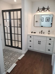 a bathroom with black and white tile on the floor next to a walk in shower