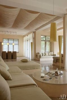 a living room filled with lots of white furniture and pillows on top of couches