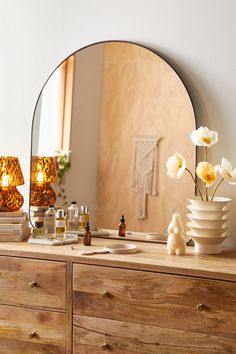 a dresser with a mirror, vase and bottles on it