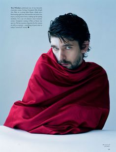 a man wearing a red cape sitting on top of a table