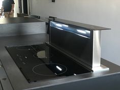 a black stove top sitting inside of a kitchen next to a person standing in the background