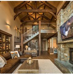 a large living room with wood floors and stone fireplace