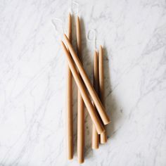 four wooden drinking straws sitting on top of a white marble counter next to each other