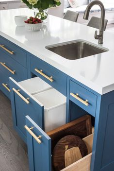 a kitchen with blue cabinets and white countertops has an open drawer in the middle