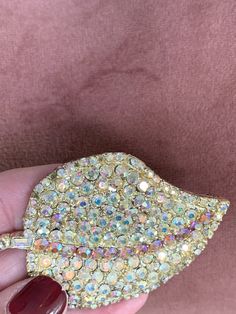 "Beautiful vintage mid century 1950's H. Pomerantz &Co. NY Leaf brooch. Aurora Borealis rhinestones with a pinkish gold tint and a darker pinkish salmonish amber color running down the middle. Due to age it looks like a couple of the rhinestones have shifted or are missing. It is hard for me to tell. I took some pictures. The shape of the rhinestones that run around the outer layer are round not baguettes which I have not seen before. Most are baguettes around the outer layer. Brooch measure Gold Crystal Brooch For Evening, Collectible Gold Brooches With Rhinestones, Gold Jeweled Brooches For Party, Vintage Gold Brooch With Bling, Gold Glamorous Party Brooch, Gold Party Brooches With Bling, Gold Glamorous Party Brooches, Glamorous Gold Party Brooches, Gold Brooches With Rhinestones For Evening