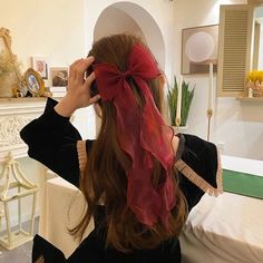 a woman with long hair wearing a red scarf on her head, sitting in front of a fireplace