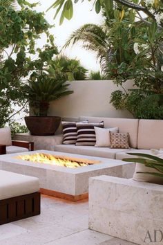 an outdoor fire pit surrounded by seating and plants