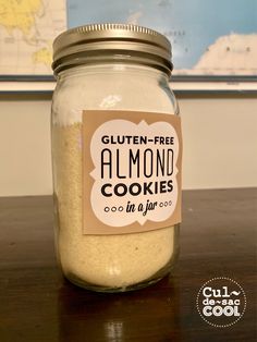 a jar filled with gluten - free almond cookies on top of a wooden table