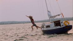 a woman jumping off the side of a boat into the water