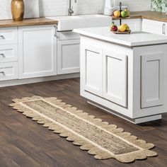 a kitchen with white cabinets and wooden flooring next to a counter top on a hard wood floor